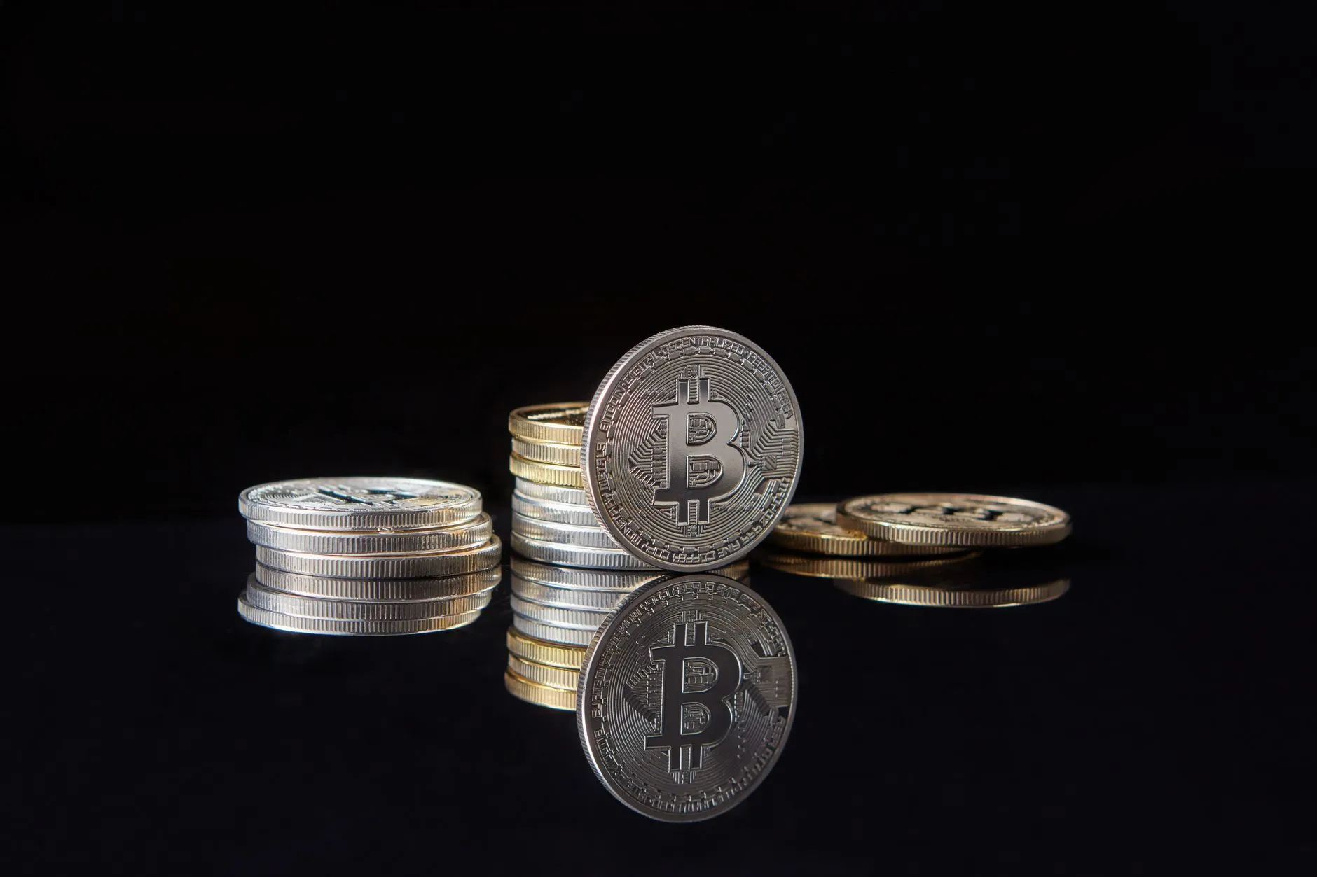 Stacked crypto coins on a dark reflective surface, illustrating token supply and emissions